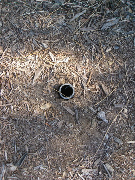 2" PVC about a foot long. Soil was excavated to leave the pipe hollow. The post slides right in. 
